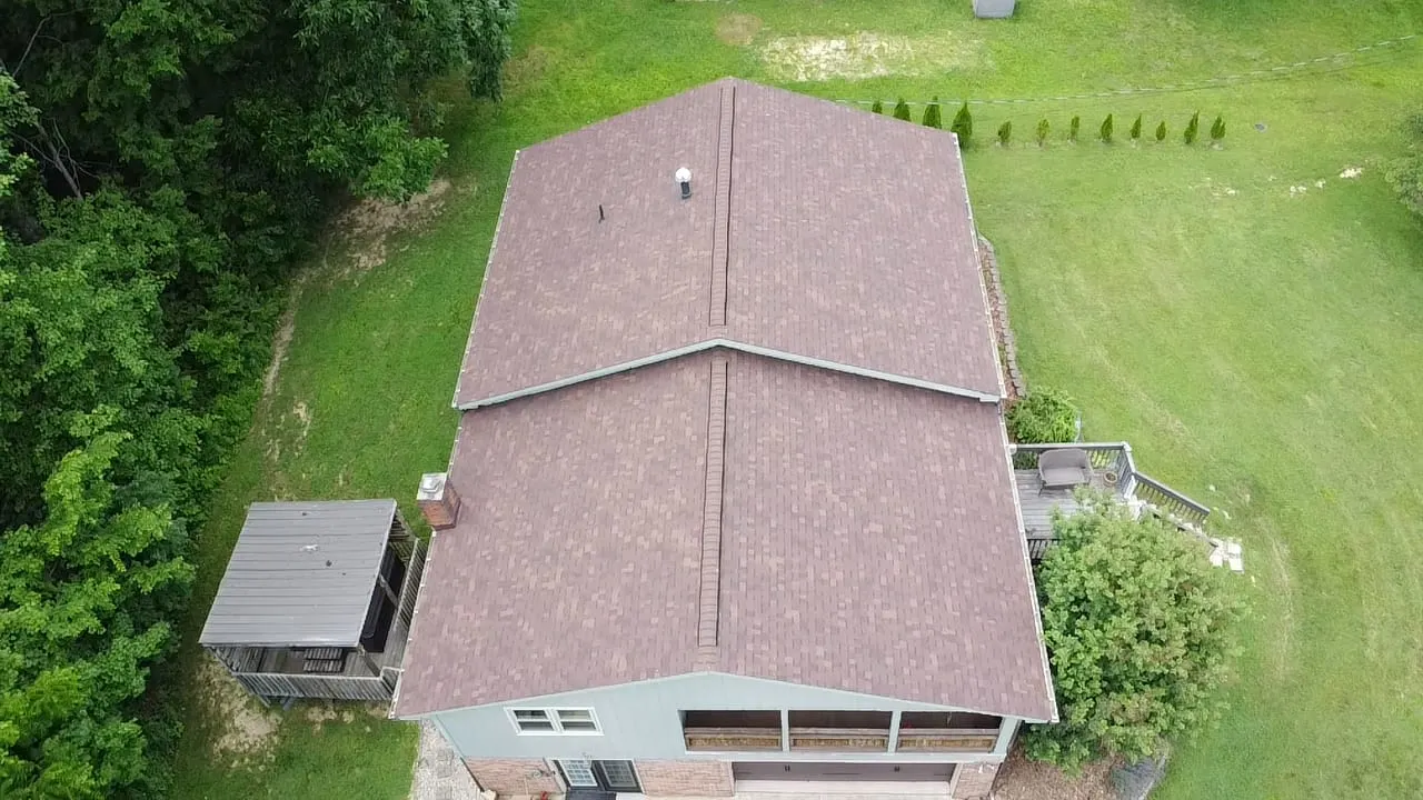 Aerial view of a finished brown roof on a home beside a large lawn