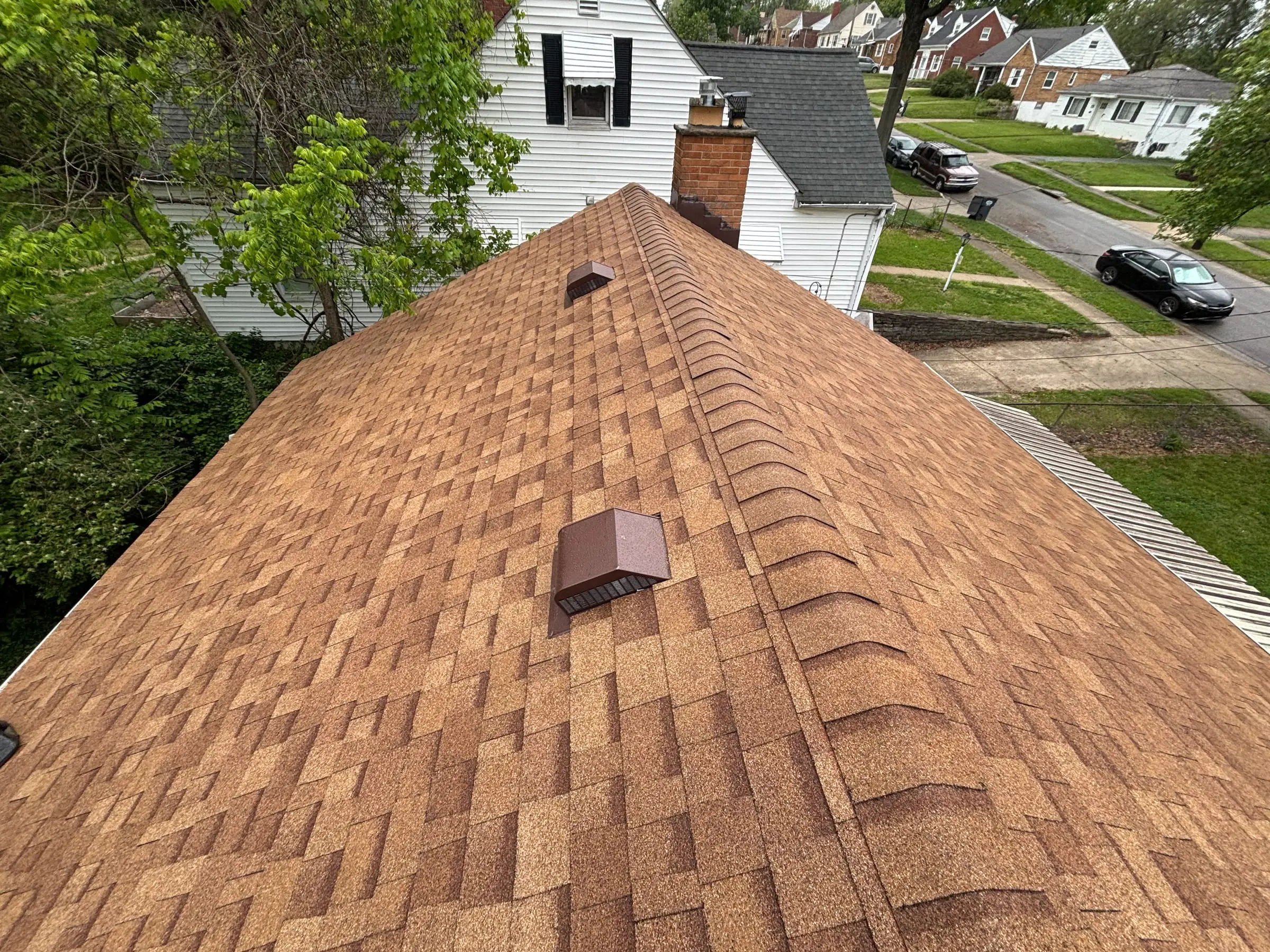 New brown architectural shingle roof with ridge cap and vents, finished by Oaks
