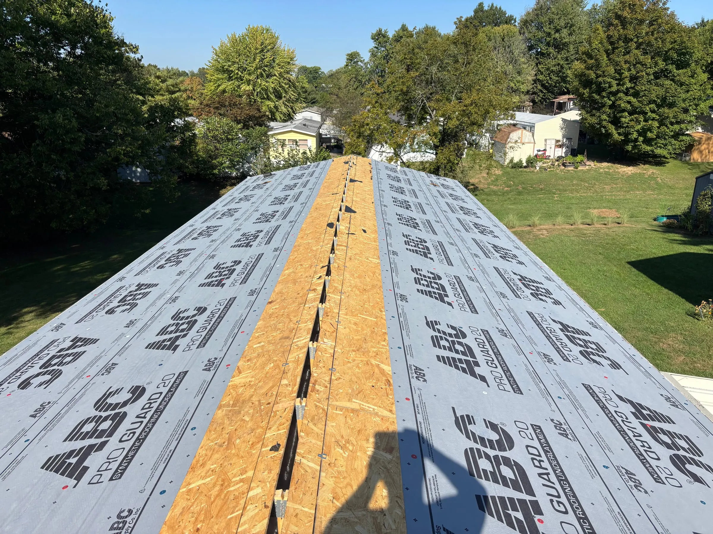 Synthetic underlayment laid over the roof deck, with the ridge vent cut open, before shingles go on