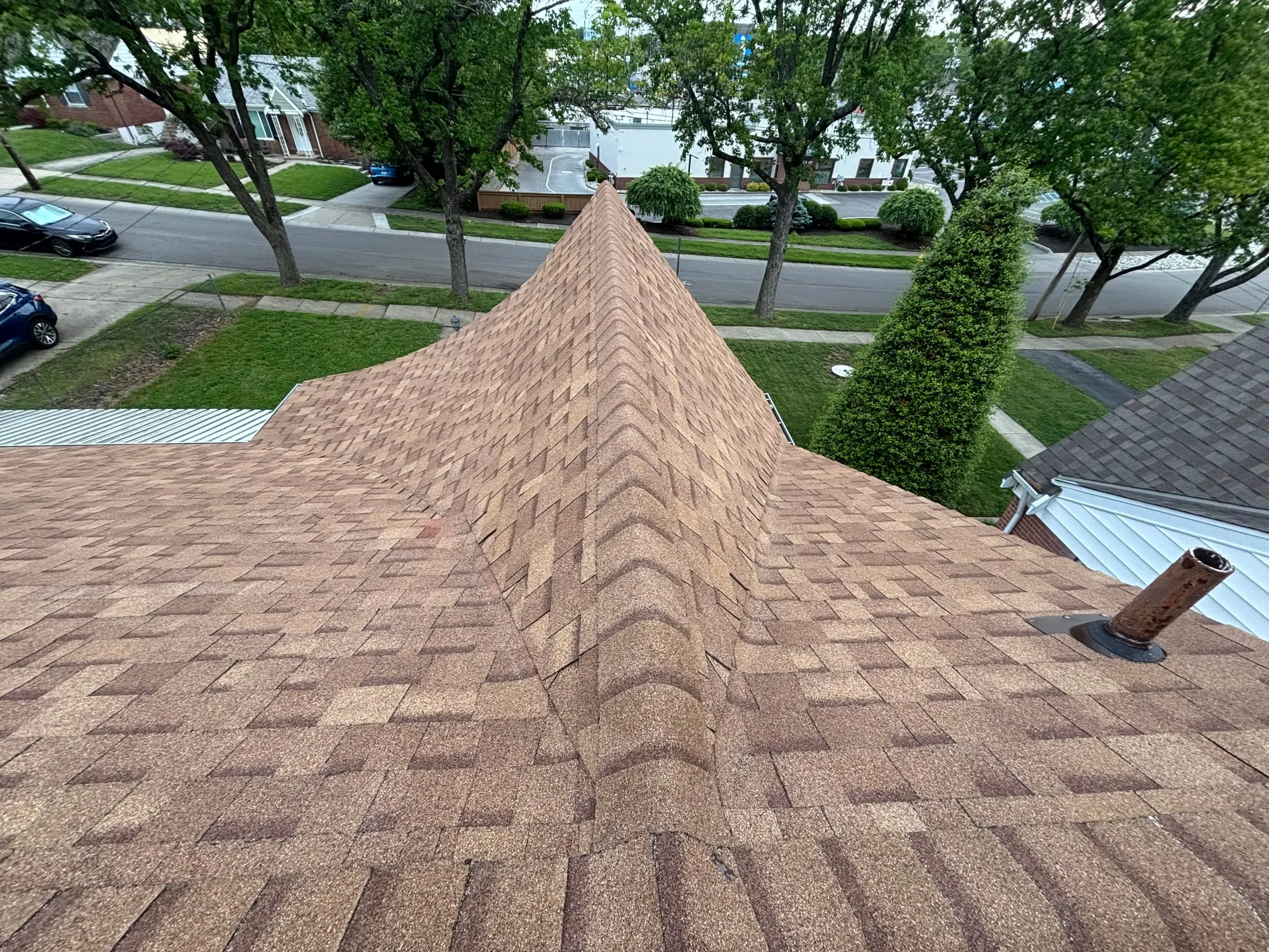 New brown shingles meeting at a hip ridge